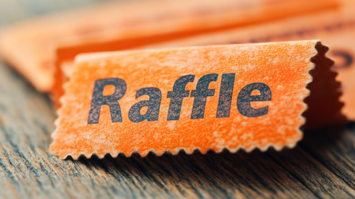 A stack of orange raffle tickets rests on a wooden table, inviting participation in a charity event